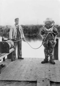 A diver in a heavy diving suit on the dock